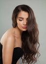 Healthy woman brunette with long shiny dark brown wavy hair, clean skin and makeup on gray background. Beauty fashion portrait, Royalty Free Stock Photo