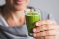 Healthy woman drinking shot of wheatgrass juice