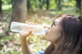 Healthy woman holding mineral drinking water in hands outdoor outside town in green park smile and looking at camera with happy Royalty Free Stock Photo