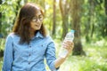 Healthy woman holding mineral drinking water in hands outdoor outside town in green park smile and looking at camera with happy Royalty Free Stock Photo