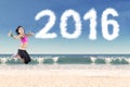 Healthy woman jumping with number 2016 at beach