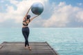 Healthy woman lifestyle balanced yoga ball practicing meditate and energy on the bridge in morning the seashore.