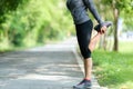 Healthy woman warming down stretching her legs ain the road outdoor. Asian runner woman