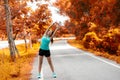 Healthy woman warming up before jogging run and relax stretching her arms and looking away in the road outdoor. Royalty Free Stock Photo