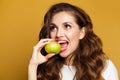 Healthy woman with white teeth biting apple fruit on bright yellow background Royalty Free Stock Photo