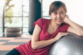 Healthy workout. Young cheerful woman sitting on the yoga mat and exercising with ball in the gym Royalty Free Stock Photo