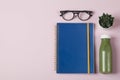 Healthy workspace with blue notebook glasses flower and green smothie on pink background Top View Flat Lay