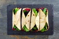 Healthy wraps with beet hummus, avocado and spinach, above view on slate