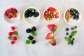 Healthy yogurt bowls with assorted berries and granola, top view with ingredients over white marble