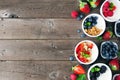 Healthy yogurt bowls with assorted berries and granola side border against a wood background with copy space