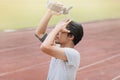 Healthy young Asian fitness man splashing water on his face after run in track of stadium. Sunshine effect. Royalty Free Stock Photo