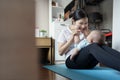 Healthy Young Asian mother sitting playing with her little cute baby boy son while practicing yoga and exercising on yoga mat at Royalty Free Stock Photo