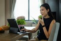 Healthy young asian woman eating apple and using computer laptop in the kitchen Royalty Free Stock Photo