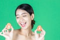 Healthy young Asian woman holding fresh tomato slice over green isolated background. Healthy and beauty skin care concept Royalty Free Stock Photo