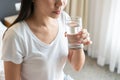 Healthy young Asian woman smiling and enjoying fresh clean water while sitting on bed in morning. Diet girl drinking water after Royalty Free Stock Photo