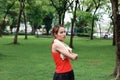 Healthy young Asian woman stretching her hands before run in park in morning. Workout and exercise concept Royalty Free Stock Photo