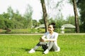 Healthy young beautiful asian woman sit and rest listening to music on earphone after running or jogging in the park in sunshine Royalty Free Stock Photo
