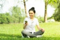 Healthy young beautiful asian woman sit and rest listening to music on earphone after running or jogging in the park in sunshine Royalty Free Stock Photo