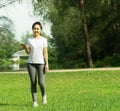 Healthy young beautiful asian woman walking and listening to music on earphone after running or jogging in the park in sunshine on Royalty Free Stock Photo