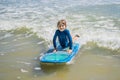 Healthy young boy learning to surf in the sea or ocean Royalty Free Stock Photo