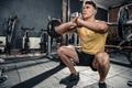 Healthy young man with curl bar performs squats