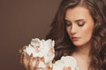 Healthy young model woman with perfect skin, brown curly hair and white orchid flowers. Facial treatment and skin care concept Royalty Free Stock Photo