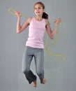 Healthy young muscular teenage girl skipping rope in studio. Child exercising with jumping high on grey background. Royalty Free Stock Photo