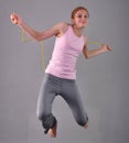 Healthy young muscular teenage girl skipping rope in studio. Child exercising with jumping high on grey background. Royalty Free Stock Photo