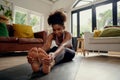 Healthy young woman doing stretching exercise sitting on fitness mat at home