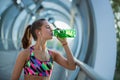 Healthy young woman drinking water and listening to music after exercising.