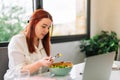 Healthy young woman eating salad while working Royalty Free Stock Photo