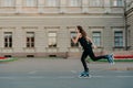 Healthy young woman has slim fit figure leads active lifestyle spends free time outside rides on rollerblades poses Royalty Free Stock Photo