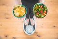 Healthy young woman looking at healthy and unhealthy food, trying to make the right choice Royalty Free Stock Photo