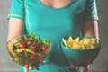 Healthy young woman looking at healthy and unhealthy food, trying to make the right choice