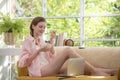 Healthy young woman lying on a couch holding a bowl of yogurt looking relaxed and comfortable Royalty Free Stock Photo