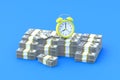 Heap of american dollars banknotes near alarm clock on blue background