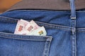 Heap banknotes of Thailand in the back of blue jeans pocket.