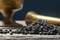 Heap of black pepper and metal mortar, milled peppercorns on wooden background, dried spice pepper corn concept Royalty Free Stock Photo