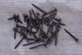 Heap of black screw nails on wooden background. Royalty Free Stock Photo