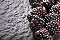 Heap of blackberries on black textured stone background with copy space.