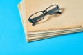 Heap of blank magazines, newspapers or some documents and modern glasses on blue desk