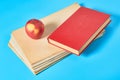 Heap of blank magazines, newspapers or some documents and red apple, book on blue desk Royalty Free Stock Photo