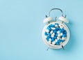 Heap of blue pills and capsules and alarm clock. Time and healthcare concept Royalty Free Stock Photo