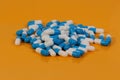 Heap of blue white capsules lie on a orange background in the studio Royalty Free Stock Photo