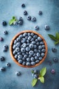 Heap of blueberry in bowl on blue table from above. Organic superfood healthy berry Royalty Free Stock Photo