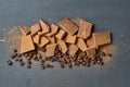 Heap of broken pieces of bitter or milk chocolate powdered of cocoa and fried coffee beans scattered on dark concrete table Royalty Free Stock Photo