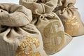 Heap of burlap bags with a gold symbol USD on them, on solid studio background