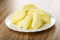 Heap of candies in shape of bananas in plate on wooden table