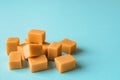 Heap of caramel vanilla fudge on a turquoise background. Fresh tasty candies made of milk and sugar. Square pieces of delicious Royalty Free Stock Photo