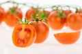 Heap of cherry tomatoes closeup and some cut in half, on white